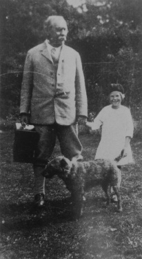 Arthur Conan Doyle holding a portable gramophone, with the gardener's daughter Eliza Ezra and his dog (ca. 1925-1930).