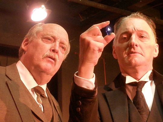 Clifford Gilkey (Dr. Watson) and Jeffrey T. Heyer (Sherlock Holmes) examine the Blue Carbuncle in the premiere production of "Holmes For The Holidays" (photo by Cynthia Womack).