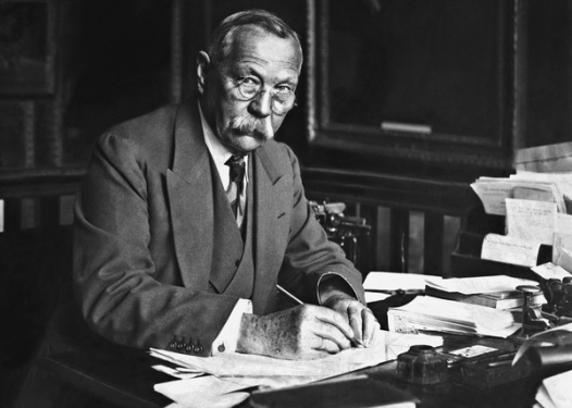 Arthur Conan Doyle writing at his desk.