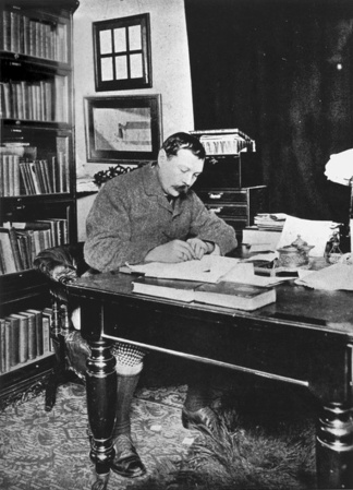 Arthur Conan Doyle writing at his desk.